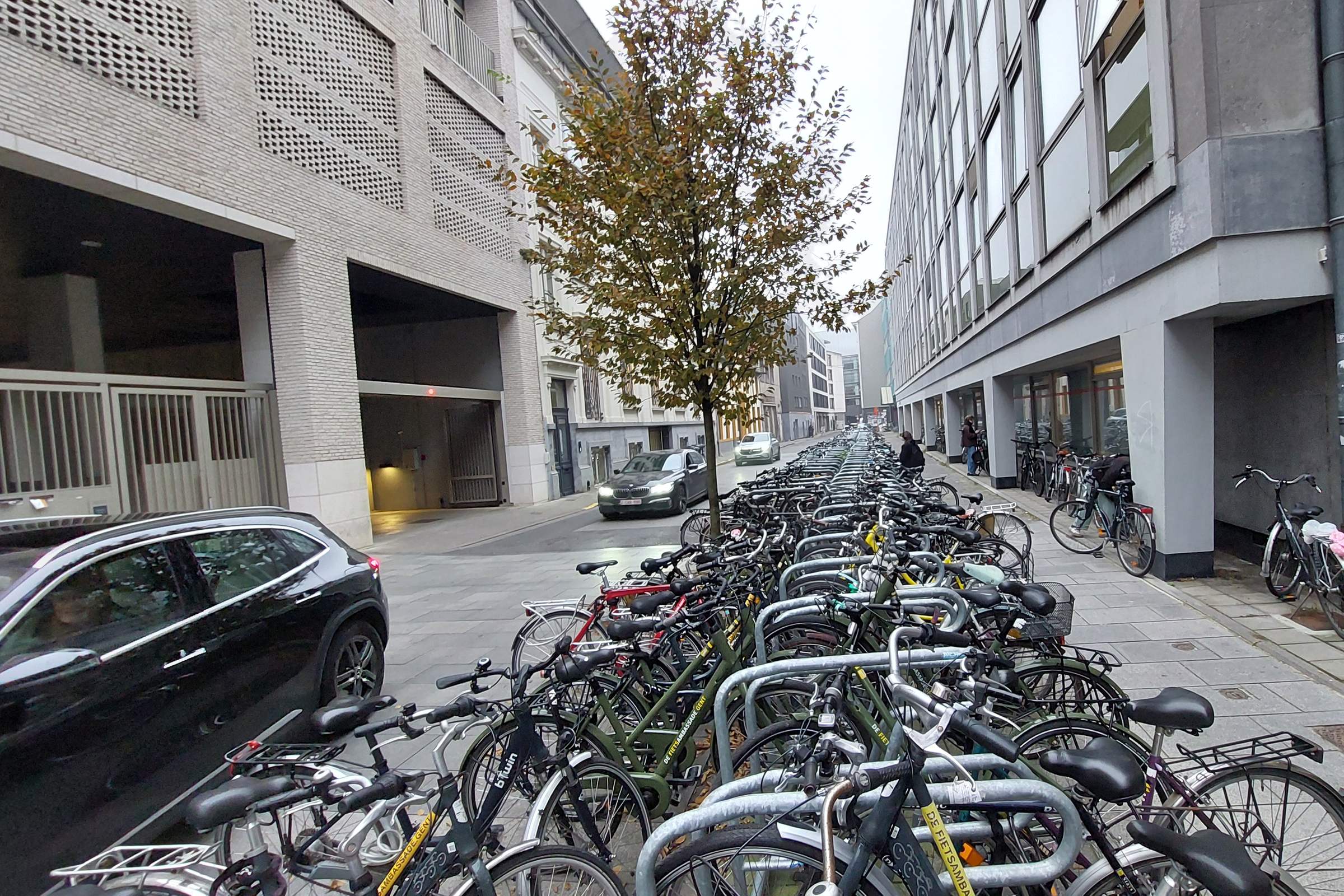 Een stationsomgeving met fietsenstalling, bushalte en wachtende reizigers