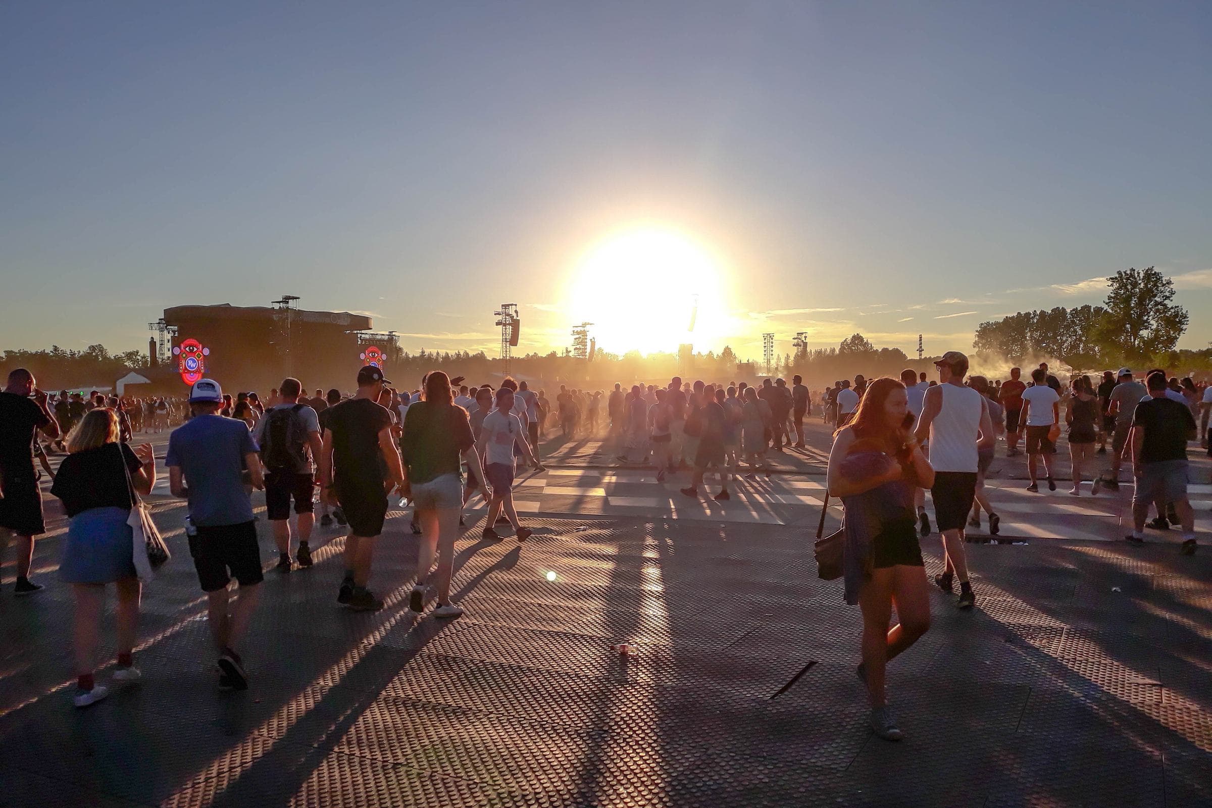 Festivalbezoekers wandelen bij zonsondergang over het festivalterrein