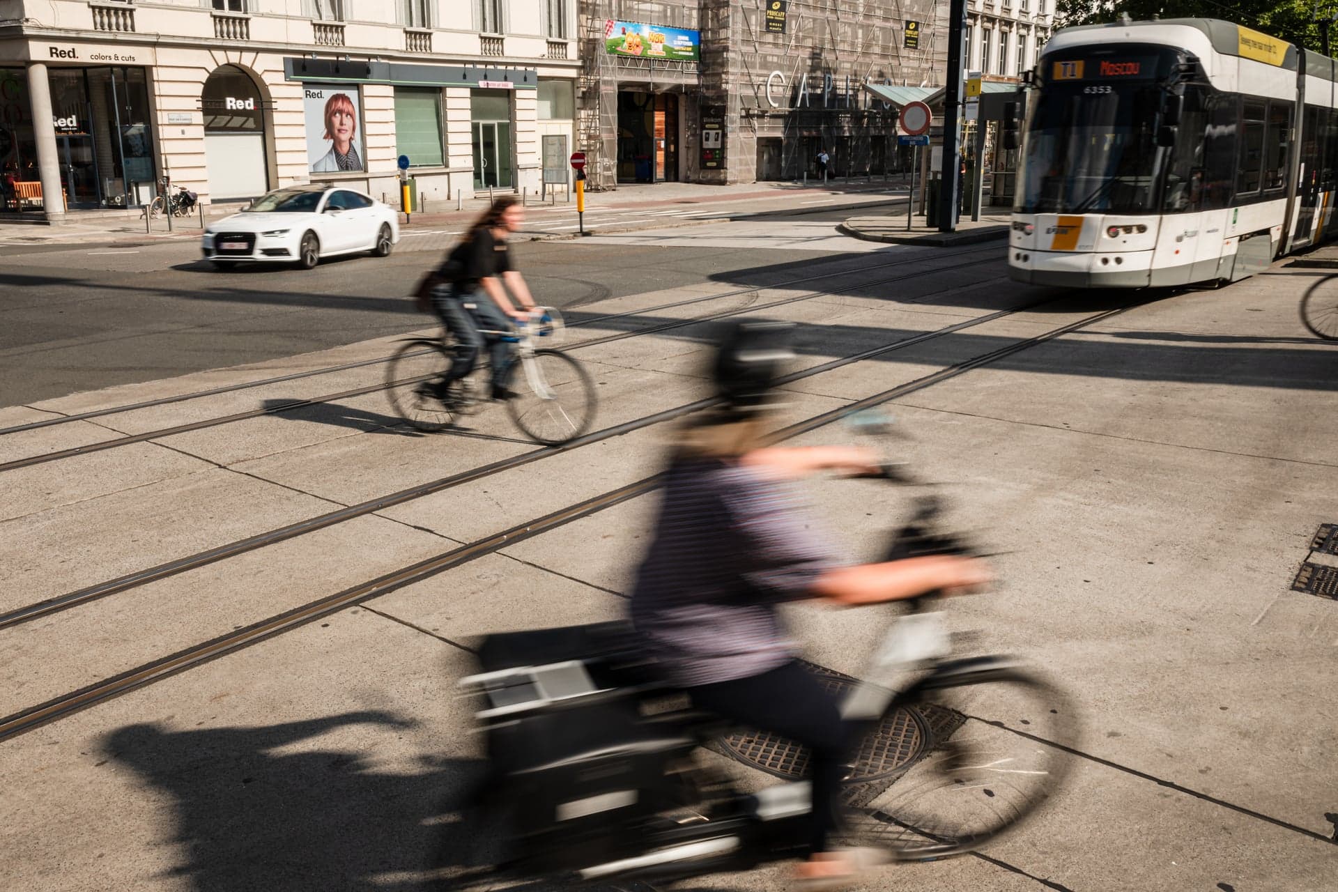 Fietsers en een tram kruisen elkaar op een druk stedelijk kruispunt